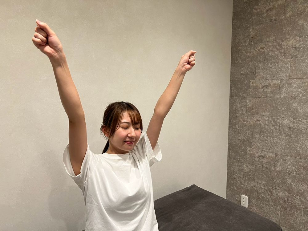 施術を終えて、両手を上げて大きく伸びをする女性