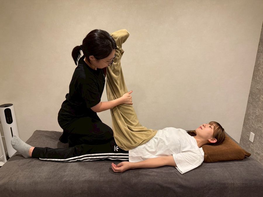 Chill Stretch の完全個室での施術。仰向けのお客様の脚をトレーナーがゆっくり伸ばしている