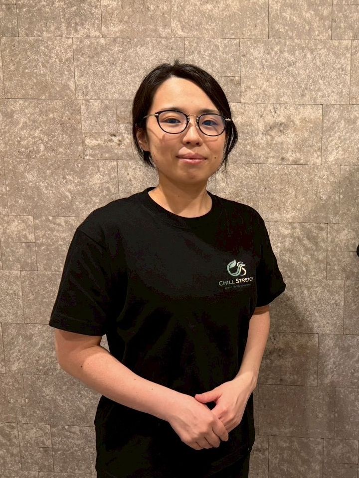 Chill Stretch セラピスト 藤森杏菜。ロゴ入りのTシャツで立つポートレート