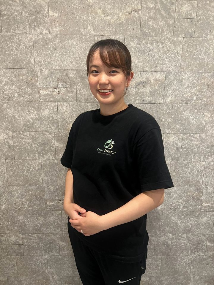 Chill Stretch セラピスト 白栁菜月。ロゴ入りのTシャツで立つポートレート